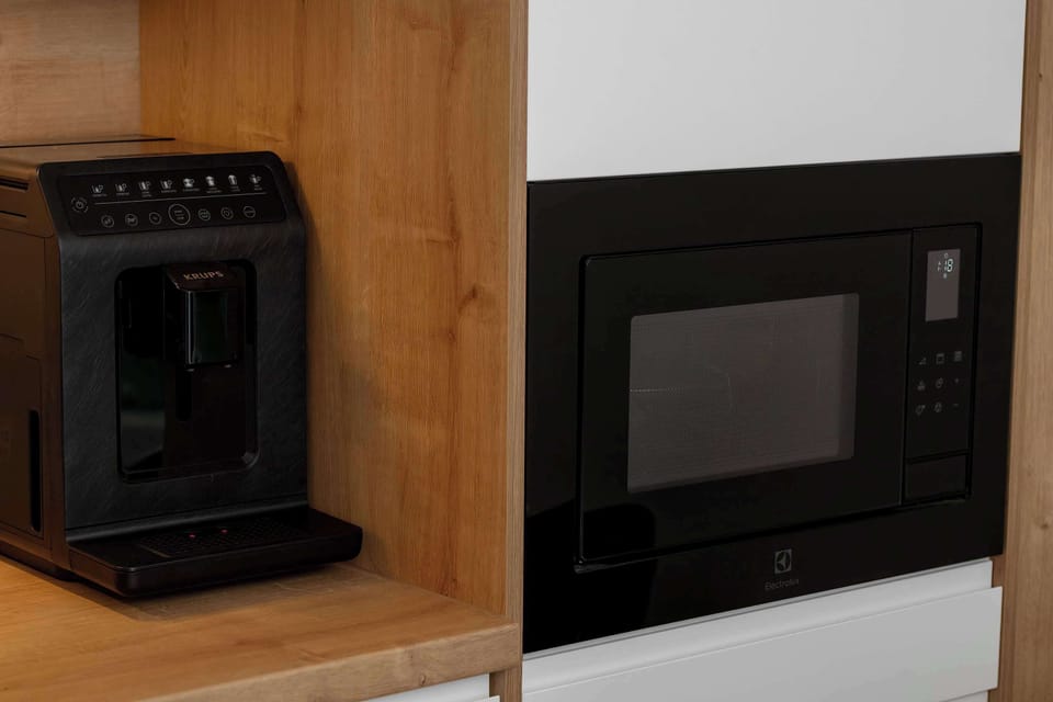 A built-in kitchen appliance area, possibly an oven or heater, set into wooden cabinetry. The finish is sleek and modern. The design blends with the rest of the kitchen.