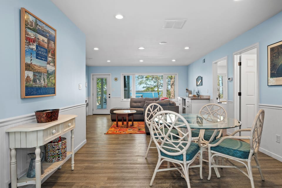Your bright coastal retreat features soothing blue walls and elegant furnishings, with natural light streaming through large windows that showcase peaceful water views.