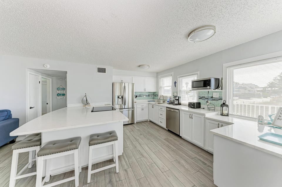 Whip up meals in your bright, modern kitchen with sleek white cabinets, stainless appliances, and an island perfect for morning coffee.