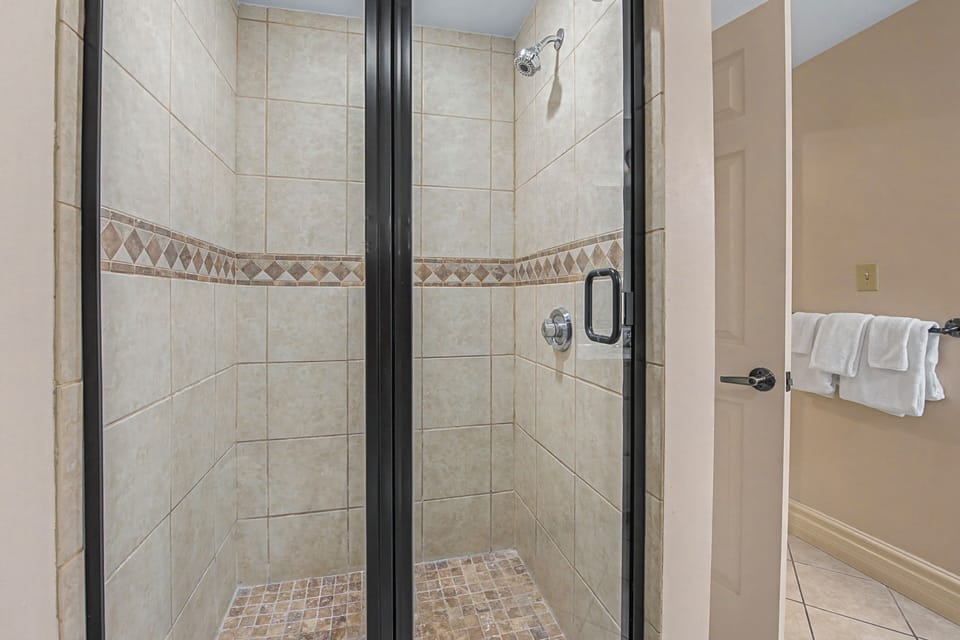 Step into your elegant tiled shower with decorative accents and glass doors—perfect for refreshing after your adventures.