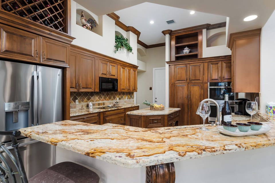 Your fully equipped gourmet kitchen features granite countertops, rich wood cabinetry, and stainless steel appliances perfect for preparing memorable meals.