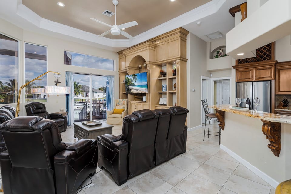 Relax in this elegant open-concept living space with plush leather seating, entertainment center, and views of the outdoor terrace through sliding glass doors.