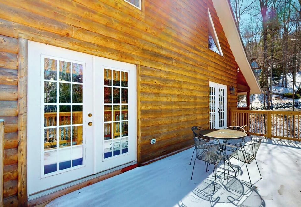 Step onto your private deck where warm log cabin charm meets winter wonderland views through the trees.