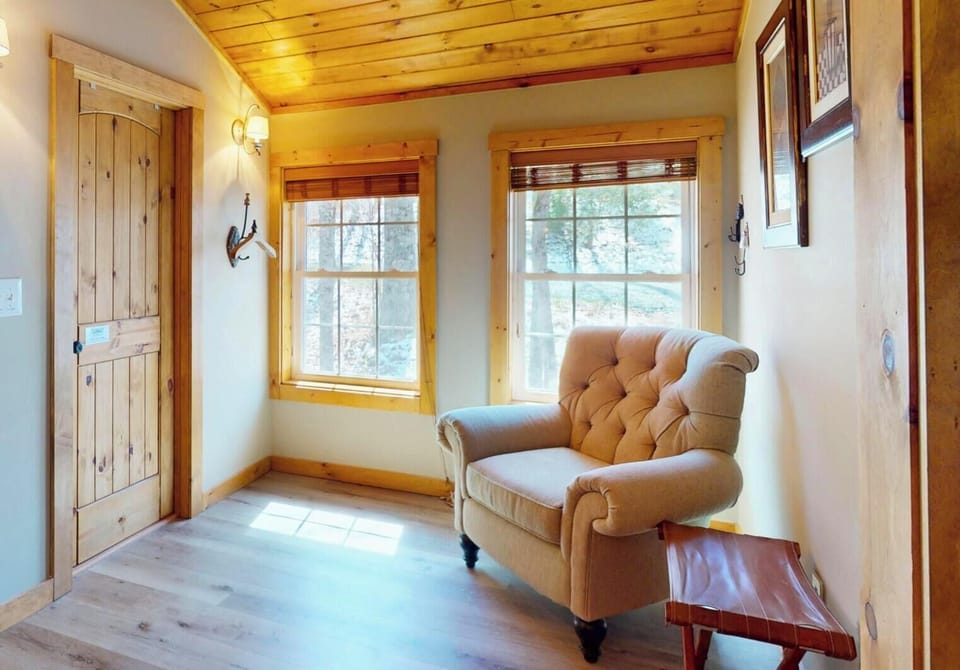 Settle into your cozy reading nook where sunlight streams through charming windows, creating the perfect spot to unwind with a book.