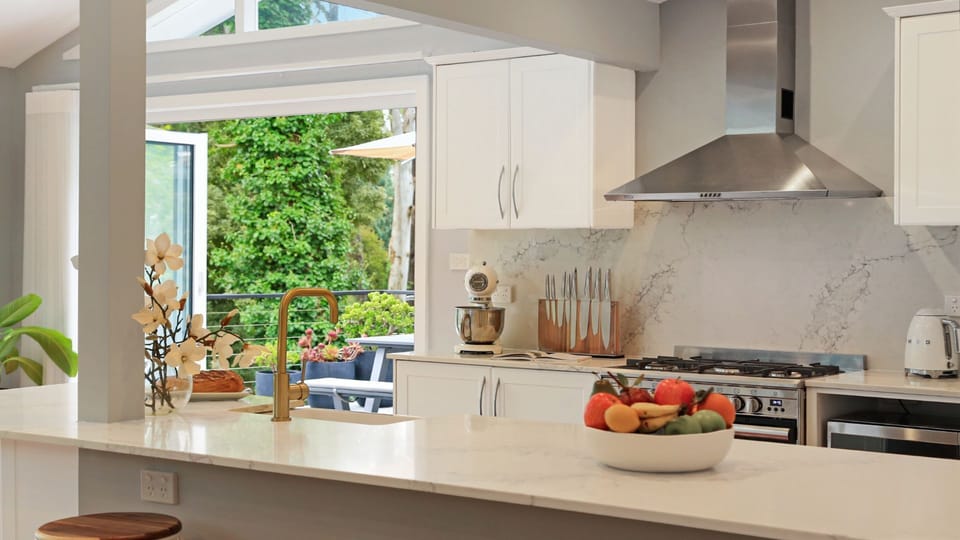 Arcadia Cottage | Kitchen with breakfast bar | Back doors open onto beautiful uncovered deck with lounges and alfresco dining | Central ducted heating throughout property