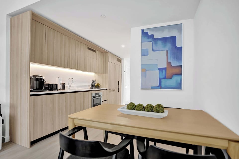 Dining table for four with art accent wall and LED-lit kitchen cabinetry visible behind.