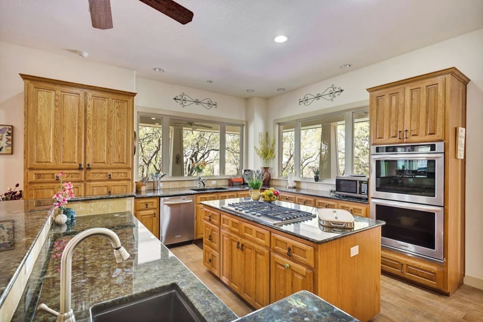 Fully equipped kitchen with island cooktop, double ovens, generous counter space, and everything guests need for easy meals during their Lago Vista stay.