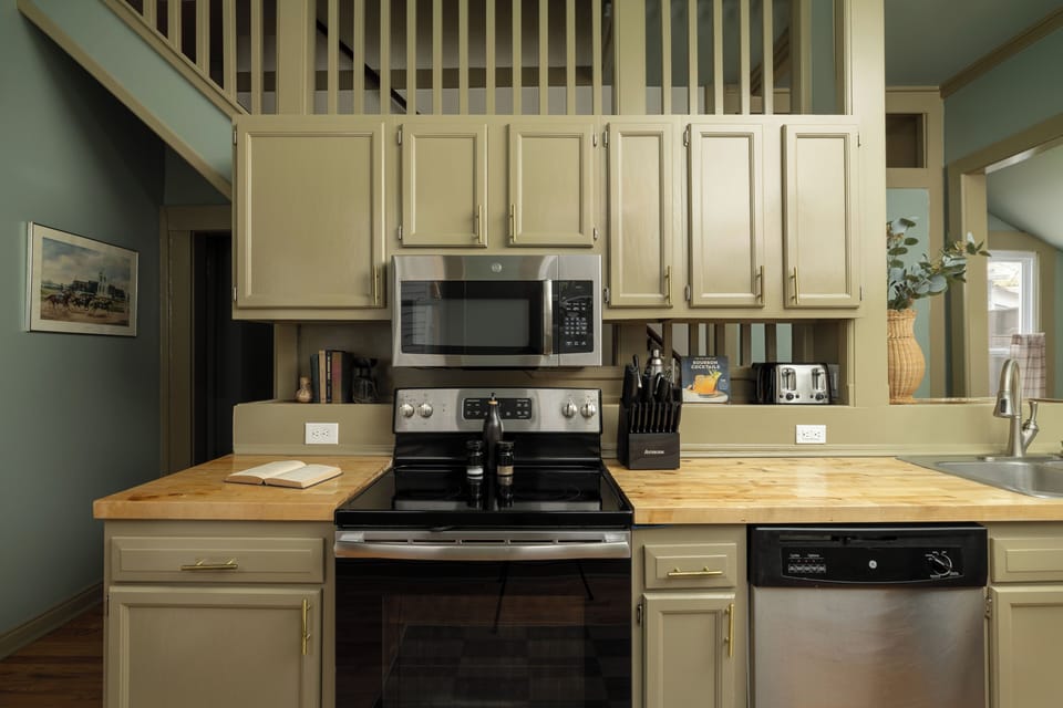 Kitchen: Sage cabinets, butcher block, and a stainless range!