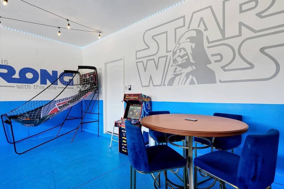 Game room with basketball arcade game, video arcade games, and seating area.