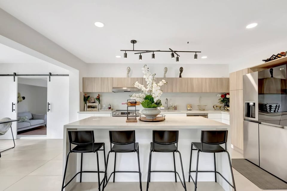 A modern open-concept kitchen with a spacious island and bar seating, perfect for cooking and gathering. Bright finishes and sleek design create a welcoming space for shared meals and moments.