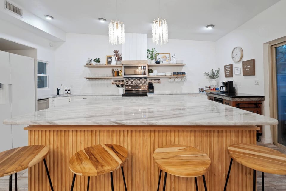 The kitchen features a spacious island bar with ample shelf space for kitchen utensils and a conveniently placed trash container on the side for added practicality.