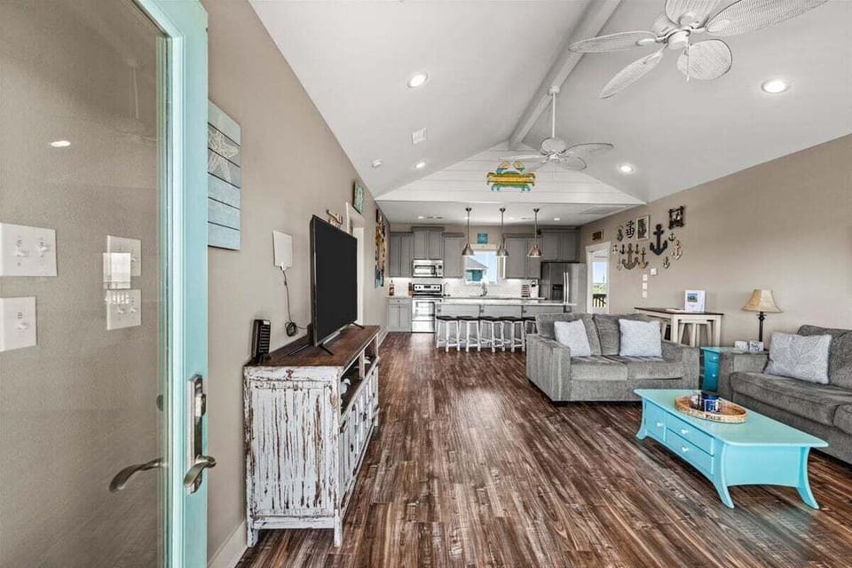Open living and dining area with coastal décor, wood flooring, and comfortable seating for large groups.