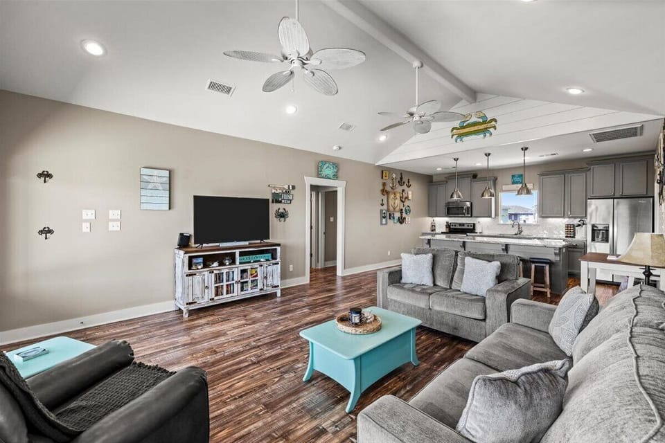 Bright open-concept living room with modern coastal décor, large seating area, and plenty of natural light – ideal for family gatherings.