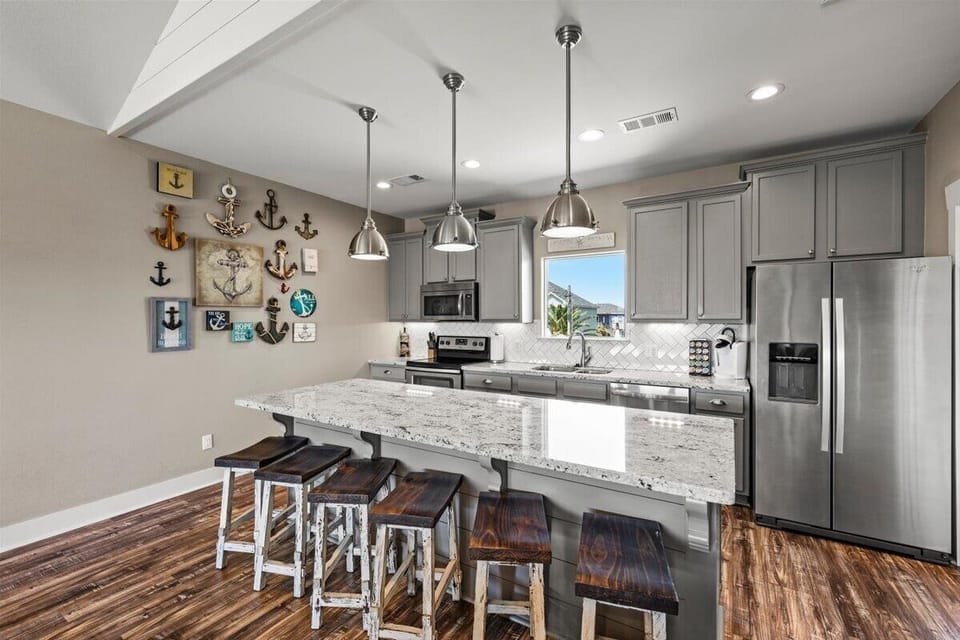 Fully equipped modern kitchen with large island, granite countertops, stainless steel appliances, and bar seating for entertaining.