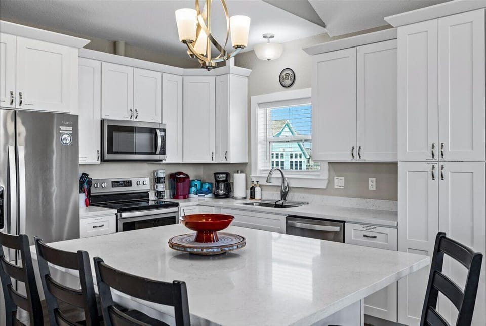 Fully equipped modern kitchen with white cabinetry, stainless steel appliances, large island, and plenty of counter space.