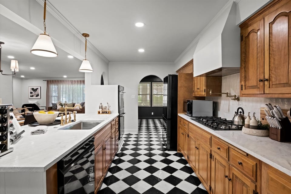 Spacious main-level kitchen with large island, quartz countertops, gas range, and ample cabinet storage. Open sightlines to the living area make this the perfect hub for cooking and gathering.