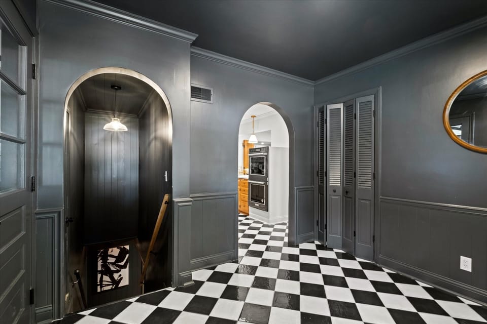 Main-level garage entryway with classic black-and-white tile leading to the kitchen and basement. An open, connected layout built for easy movement throughout the home.