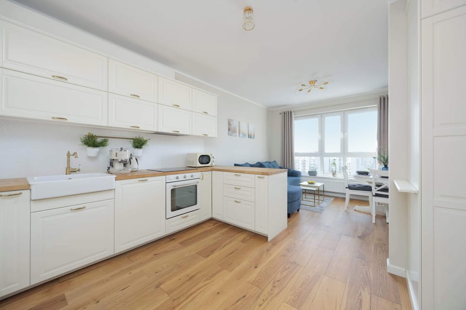 A spacious kitchen with white cabinetry, wooden floors, and a wide open layout.