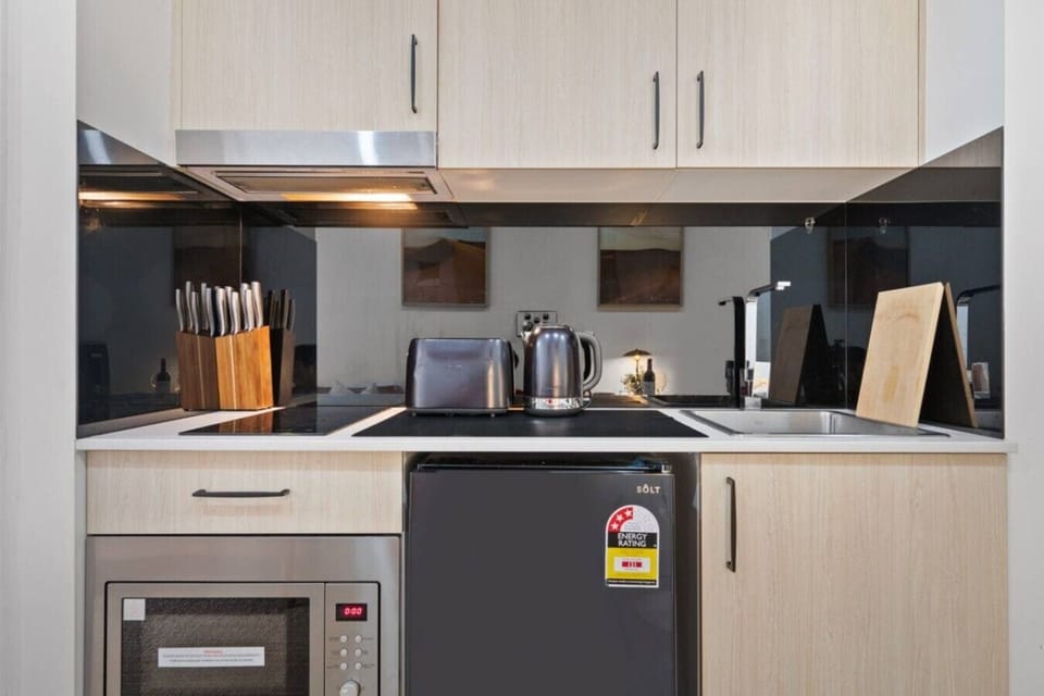 Compact, fully equipped kitchen with cooktop, microwave, kettle, toaster, and essentials for easy home-style meals.