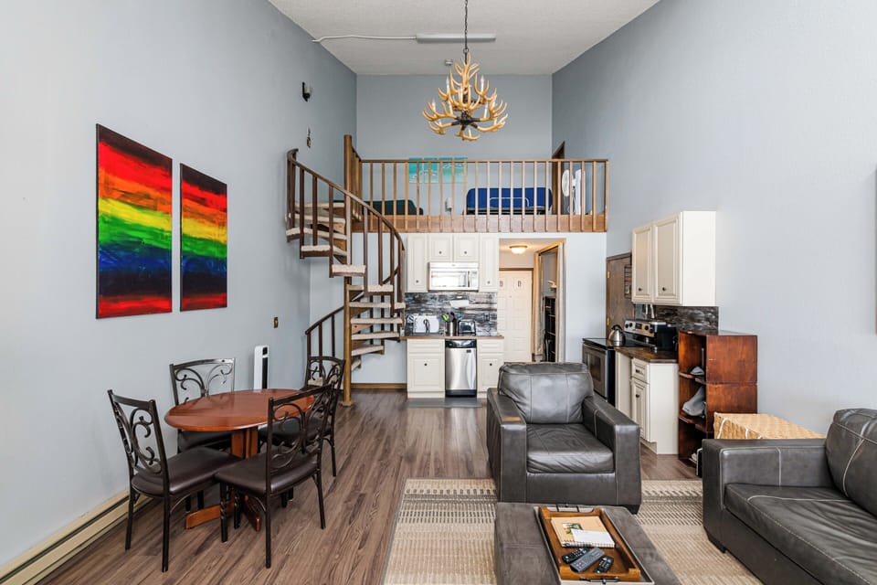 Your spacious loft at 643 SilverCreek Inn features soaring ceilings with a striking antler chandelier, leather seating, and a spiral staircase leading to your private upstairs retreat.