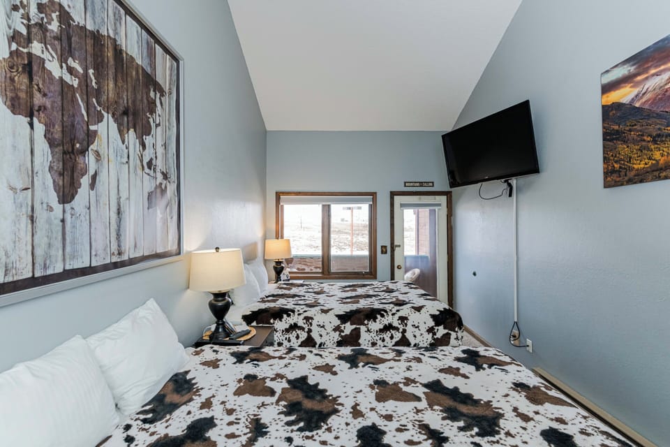 Your restful retreat features a cozy bed with unique cowhide print bedding, inspiring world map art, and modern amenities including TV in 645 SilverCreek Inn.