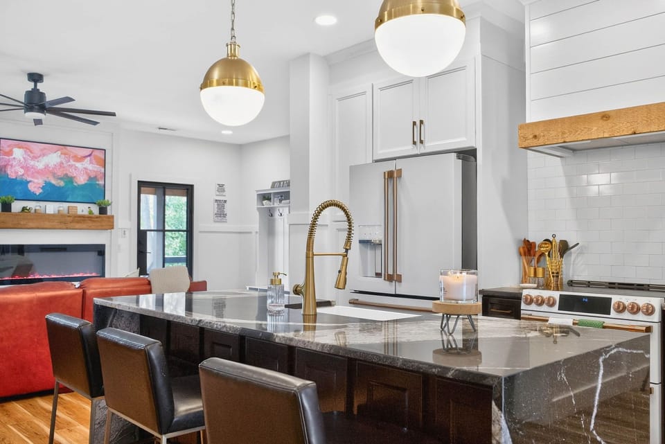 Elegant pendant lights and a gold faucet pair beautifully with a large farmhouse sink, adding both style and functionality.