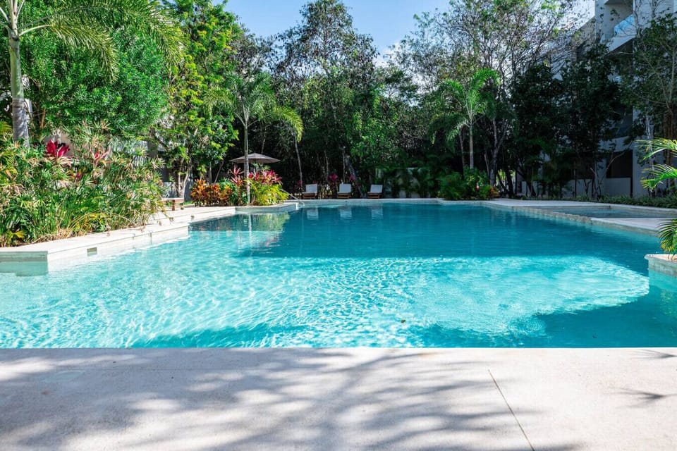 Large resort-style swimming pool surrounded by tropical nature – a peaceful oasis in Playa del Carmen.