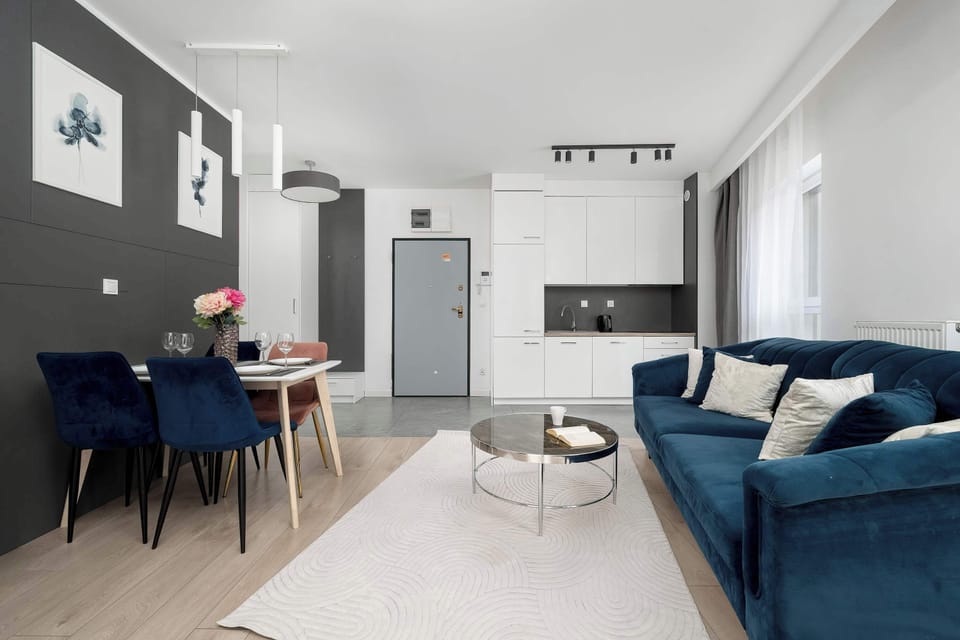 A perspective from the kitchen looks out toward the living room and the navy blue sofa. The open-concept design makes the apartment feel connected and ideal for social gatherings.