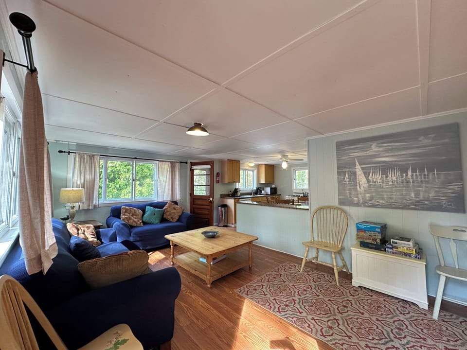 Relax in your cozy living room with plush navy seating, nautical art, and natural light streaming through the windows.