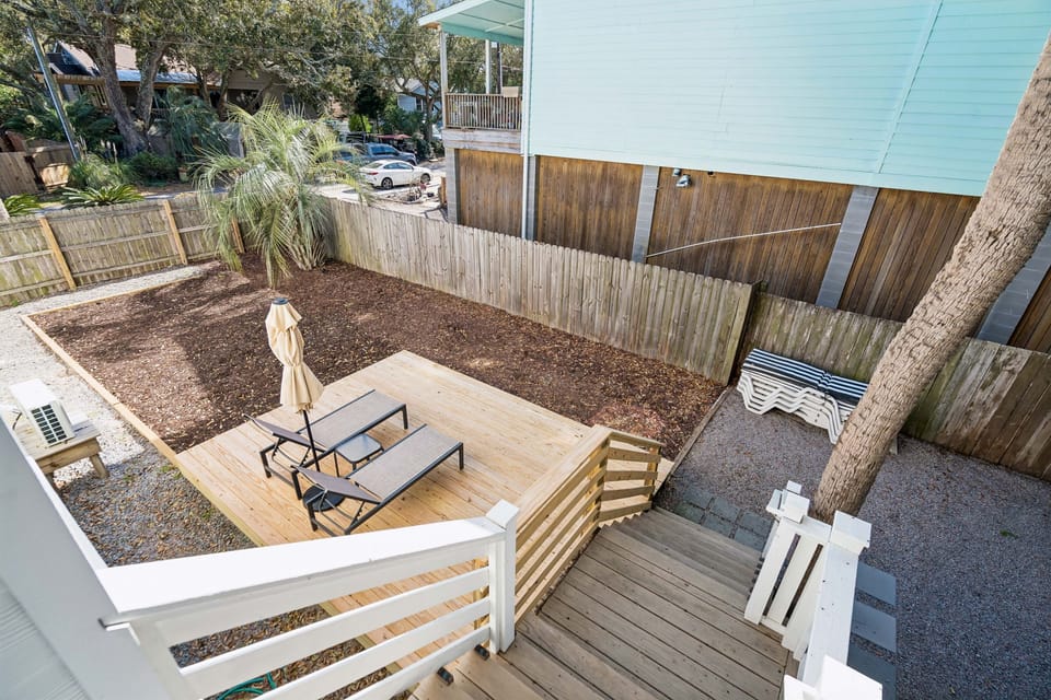 Your private backyard oasis features a spacious wooden deck perfect for morning coffee, surrounded by mature palms and garden space.