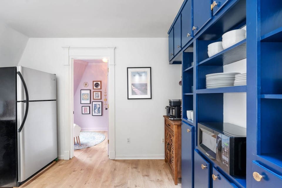 Bright kitchen with full-size fridge, coffee station, and open shelving.