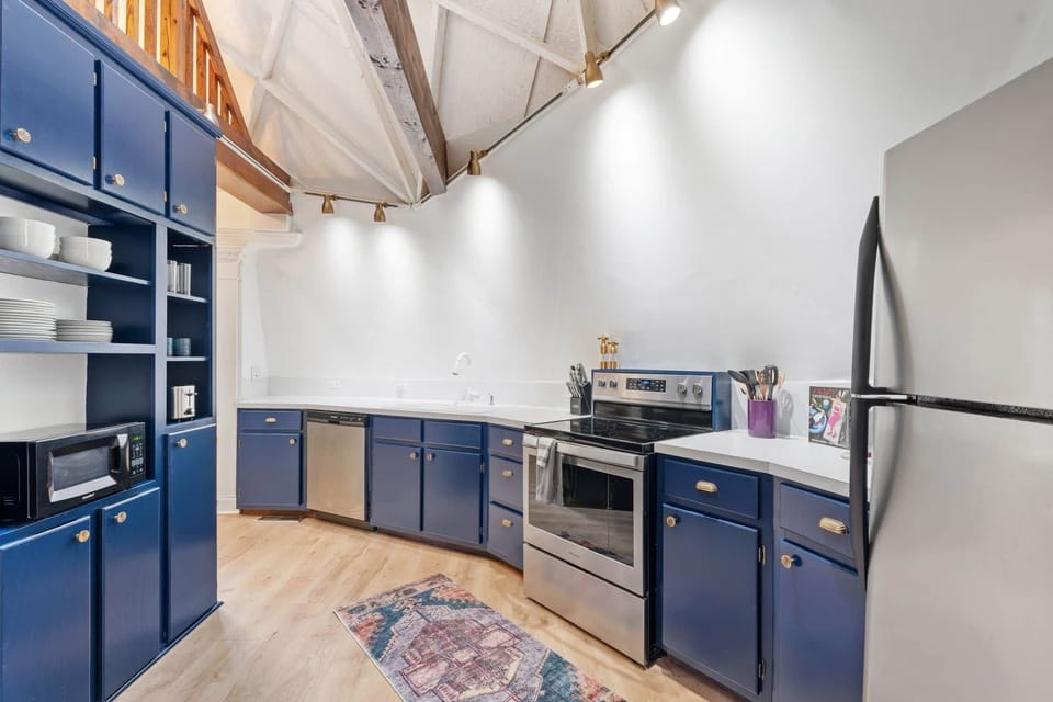 Modern kitchen with full-size appliances, blue cabinetry, and vaulted dome ceiling.