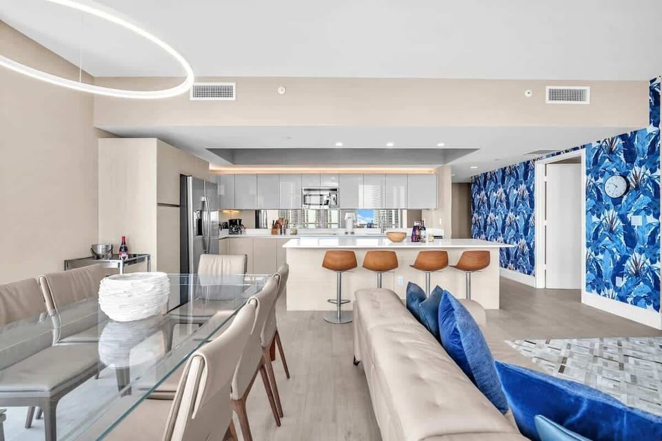 Elegant dining area featuring a modern glass table with seating for up to 8 guests, offering a comfortable setting for shared meals.