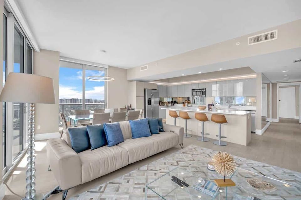 Spacious living area featuring a large flat-screen TV and a modern kitchen with a breakfast counter and stylish bar seating.