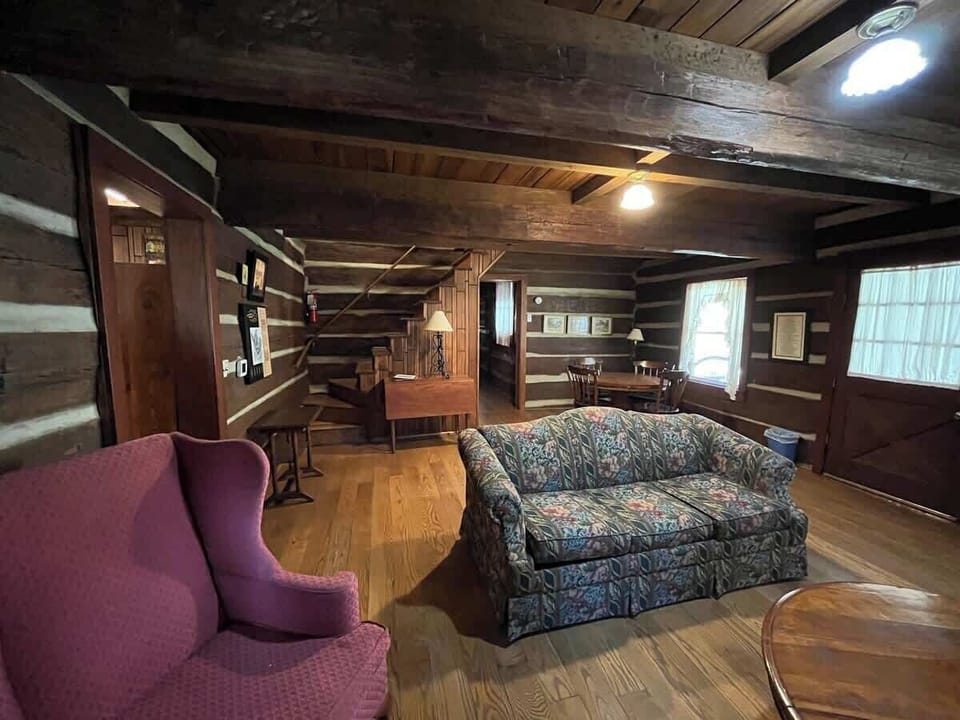 The living room allows for access to all other parts of the inn. The front door is to the right, the kitchen is to the left, the first floor bedroom is straight ahead down the hall, and the second floor bedroom is up the stairs.