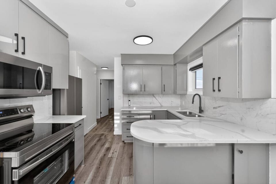 Modern kitchen with quartz countertops, island sink, and stainless steel appliances.