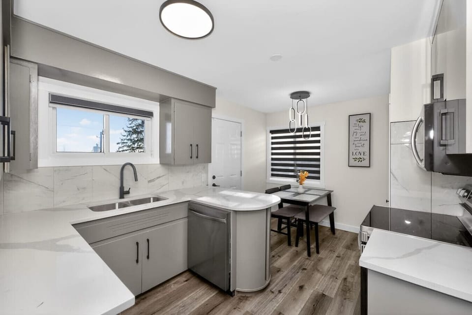 Modern kitchen with stainless steel appliances, quartz countertops, and dining area.