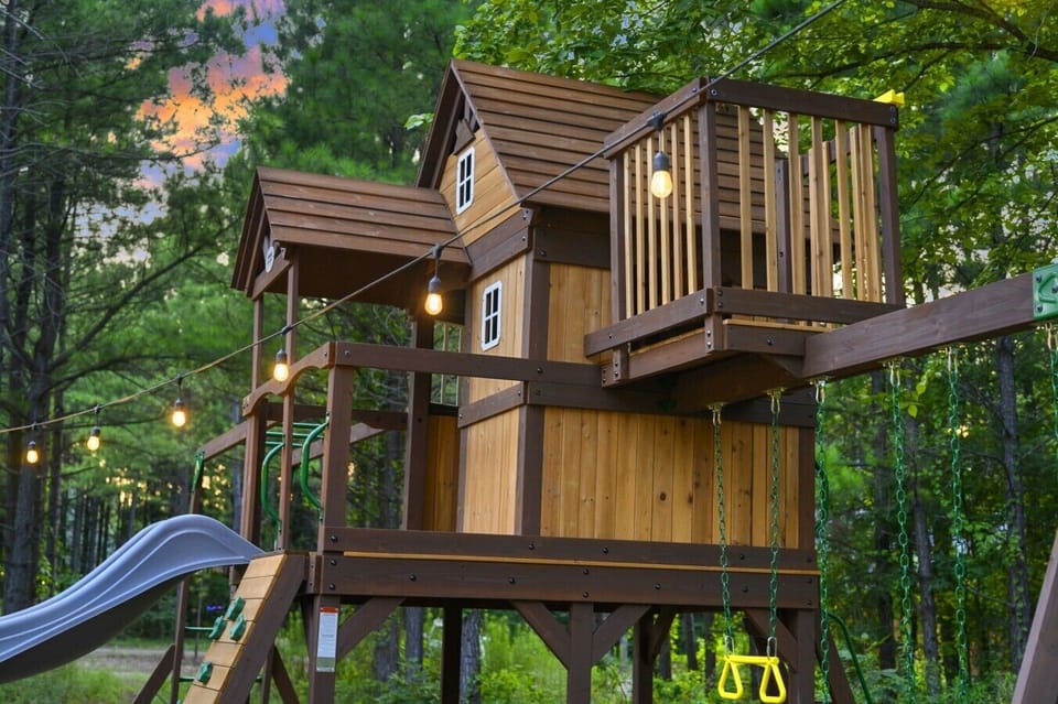 Treehouse playset with slide and swings for family-friendly outdoor fun.