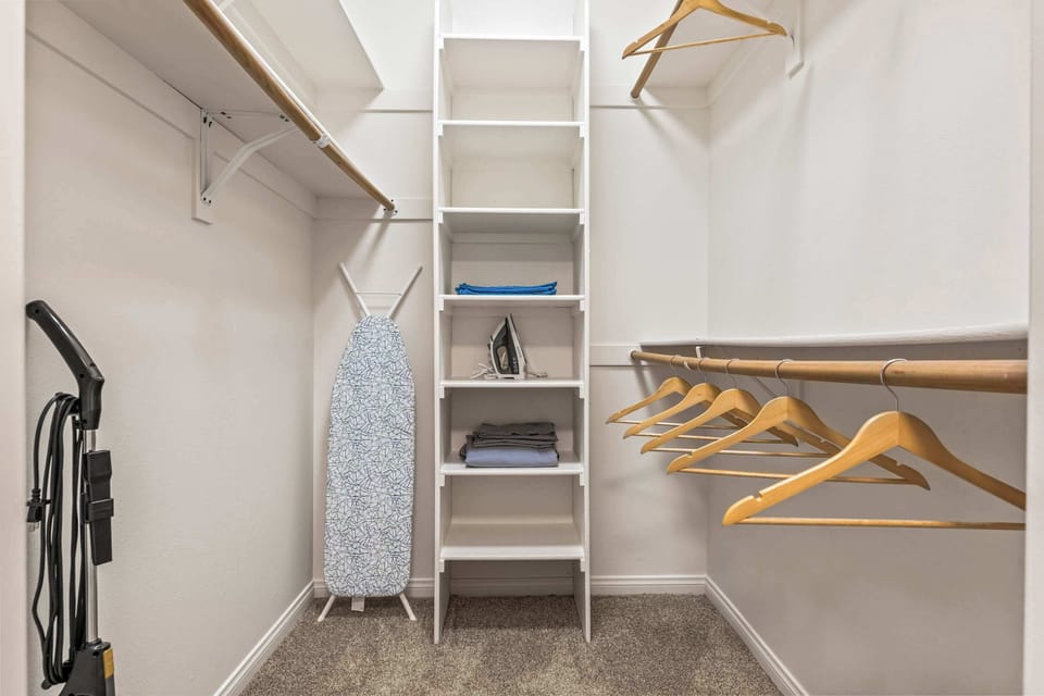 Organized storage space with shelves, hangers, and essentials like an ironing board for your convenience.