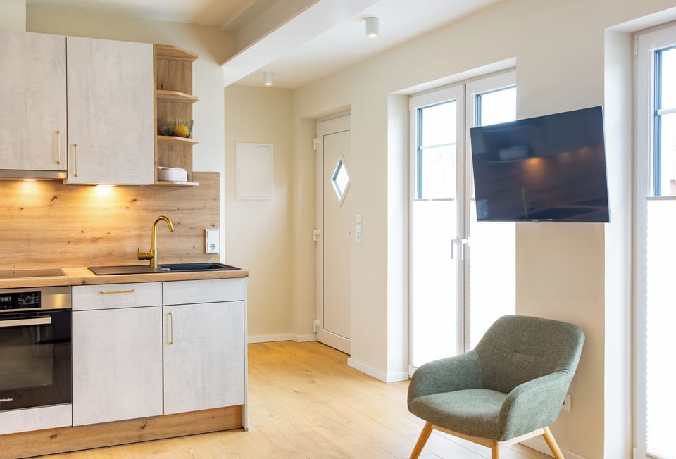 Apartment Salz/House Queller in Wittdün/Amrum   Open-plan kitchen with a view of the entrance area and a TV