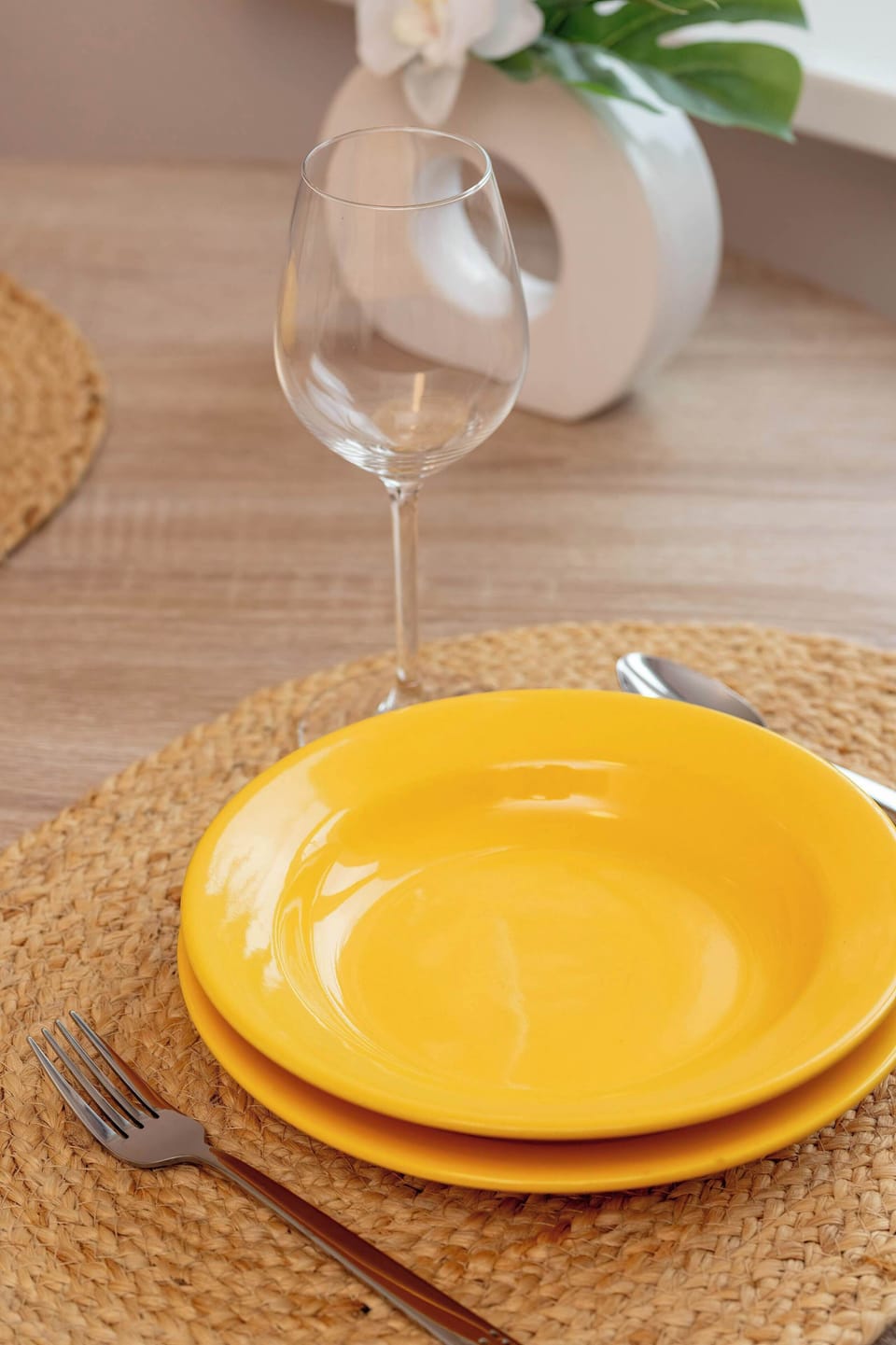 A close-up of a breakfast setting with a bowl and a drink on a table. The arrangement is simple and neatly placed. Warm tones make the scene inviting.