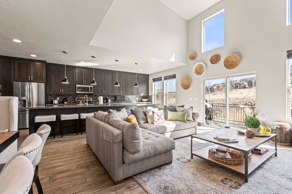 Relax in your open-concept living space featuring modern furnishings, a fully equipped kitchen, and stunning natural views through floor-to-ceiling windows.