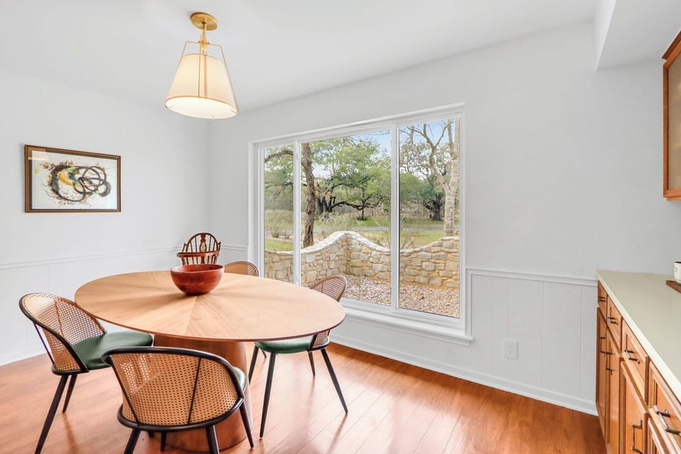 Savor meals at your elegant dining table while gazing through expansive windows at peaceful garden views and natural stone features.