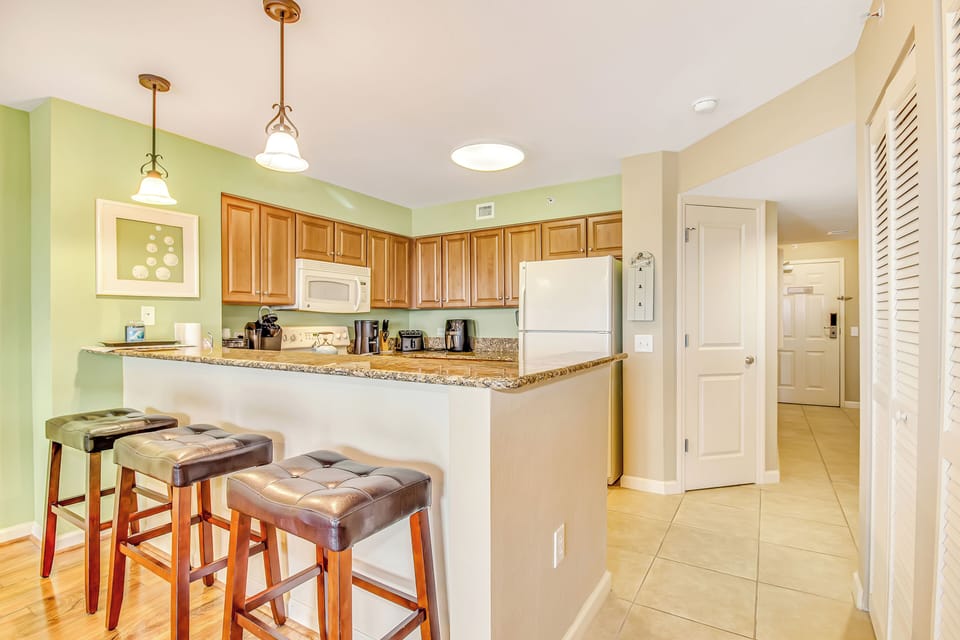 Cook your favorite meals in this bright, fully-equipped kitchen featuring granite countertops, modern appliances, and a breakfast bar for casual dining.