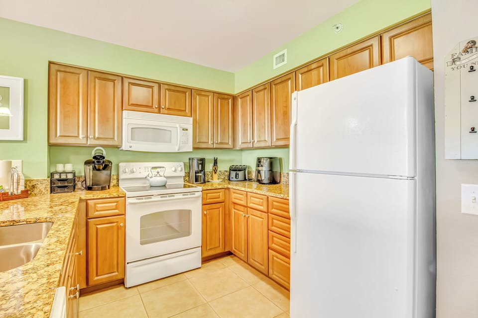 Your fully-equipped kitchen awaits with gleaming countertops, warm wood cabinets, and everything you need to create memorable meals.