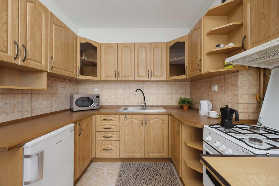 A functional wooden kitchen is equipped with built-in cabinetry, a microwave, a sink, and essential cooking appliances.