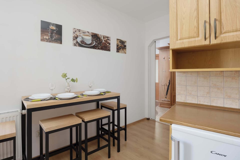 A high-top wooden table with four black stools provides an alternative dining or workspace area against a white wall.