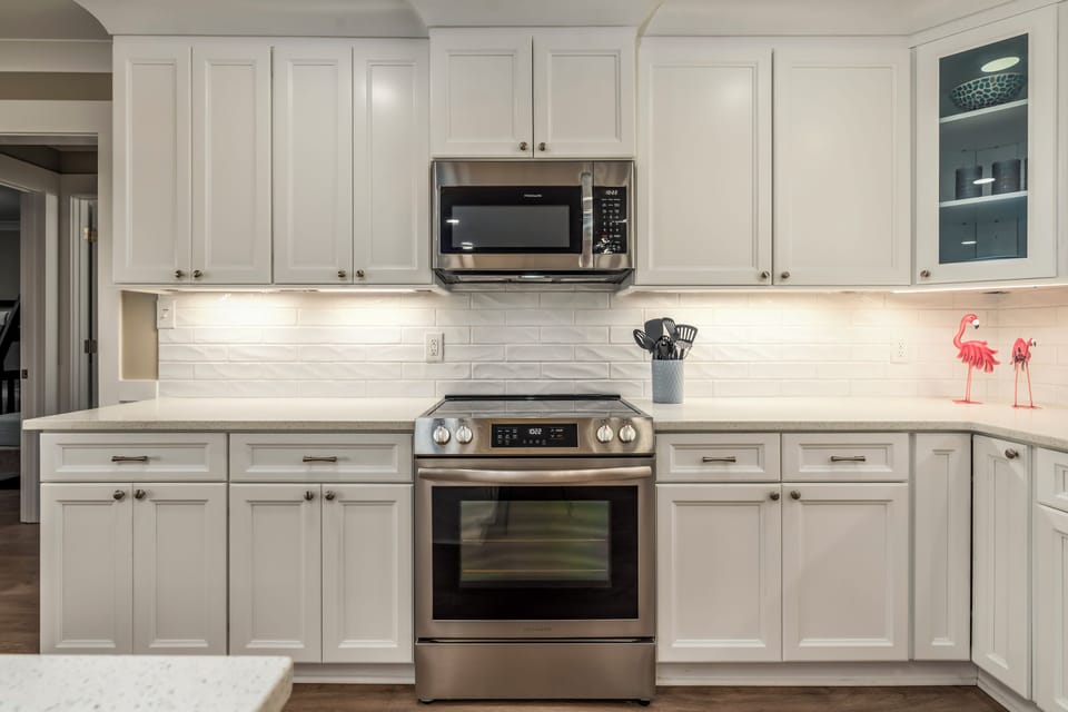 Your fully equipped kitchen features crisp white cabinetry, granite countertops, and modern appliances ready for your culinary adventures.