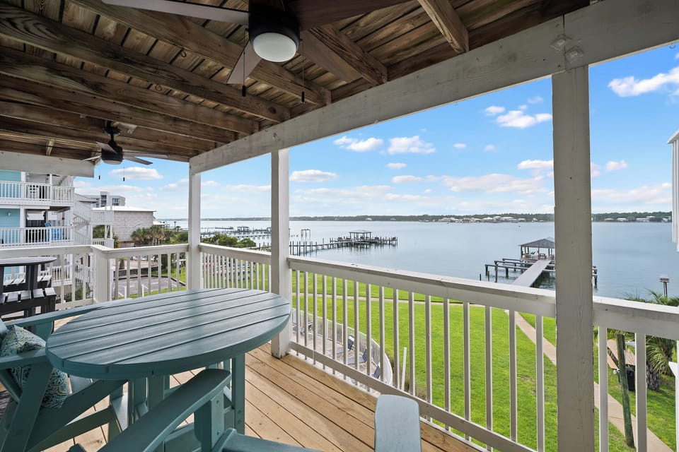 Covered waterfront balcony with dining space and peaceful dock views