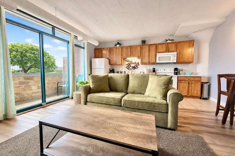 Spacious open-concept layout with comfortable sofa, modern coffee table, and easy flow between kitchen and living area. Designed for relaxation and connection.